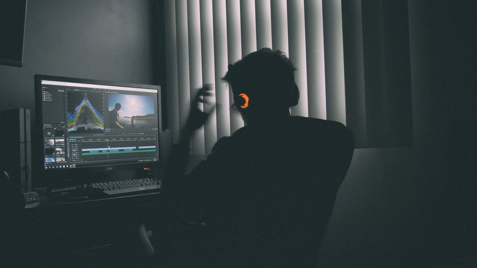 Karanlık odada monitör başında video kurgusu yapan içerik üreticisi
